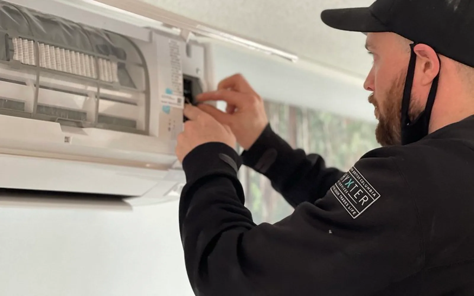 Licensed photo: technician near an open ductless mini-split indoor unit